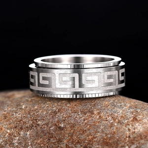 Macro detail of men's spinning ring with geometric pattern on a rustic stone base