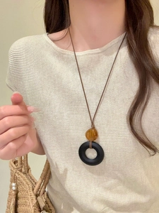 Close-up of geometric resin pendant necklace with wood texture and amber beads on a model