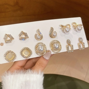 Close-up of elegant gold earrings set featuring rhinestones and faux pearls on a card