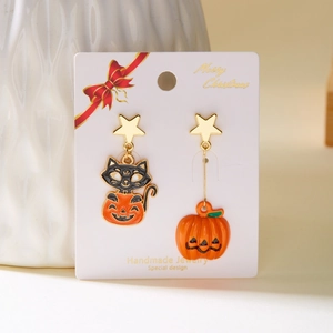 Detailed macro of Halloween earrings featuring black cat on pumpkin and star studs