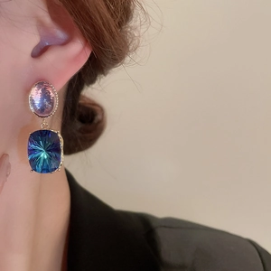 Detail of vintage gold plated earrings featuring purple and blue-green gemstones on model