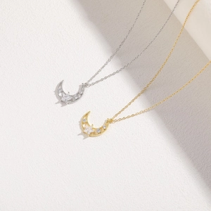Detailed close-up of gold and silver moon and star pendants with inlaid white zircon