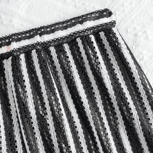 Macro view of black and white vertical striped mesh fabric with lace texture detail