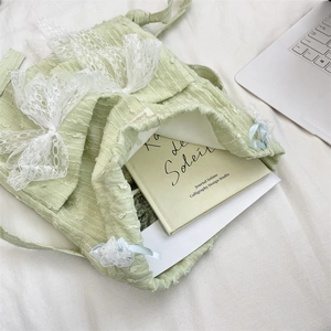 Light green lace drawstring backpack with book inside showing storage capacity.