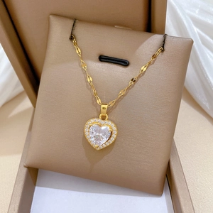 Detail of heart pendant necklace in gold finish with sparkling central zircon and micro-pave