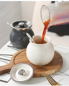 Detail of ceramic seasoning jars with wooden lids and spoons in a modern kitchen setting