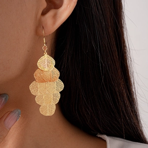 Detailed view of long gold tassel earrings with irregular hollow leaf-shaped design
