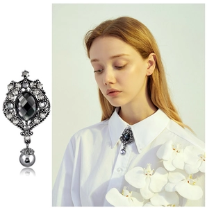 Detail of baroque cross brooch with black crystal center and hanging grey pearl drop