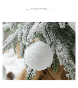 Close-up of white flocked Christmas snowballs with pine needles and festive background