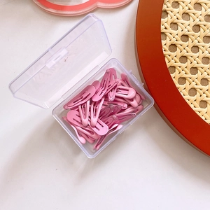 Detailed view of pink metal BB hair clips in a transparent plastic storage box