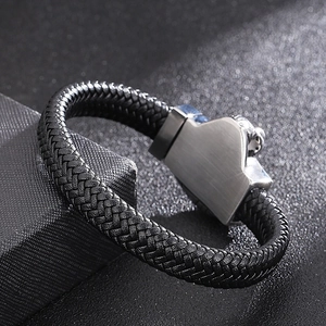 Détail d'un bracelet en cuir tressé noir avec fermoir géométrique en métal brossé