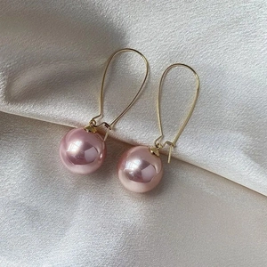 Detail der rosa-violetten Perlen an goldenen langen Haken auf seidigem Satin-Hintergrund