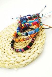 Detail of colorful Bohemian hand-woven surf bracelets on a rustic round woven mat