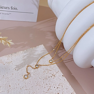 Detail of gold double-layered necklace with sparkling zircon stones on marble texture