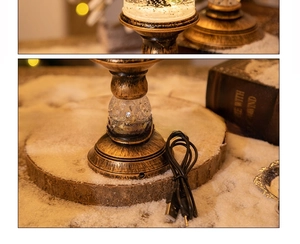 Close-up of vintage bronze crystal candle lamp with a USB charging cable and snow globe base
