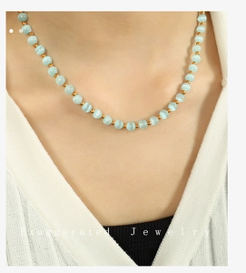 Close-up of mint green cat eye beads and gold metal spacers on a stainless steel necklace