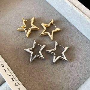 Detail view of gold and silver cutout star earrings on a premium grey velvet jewelry tray