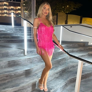 Pink satin slip dress with dynamic fringe detailing shown in a professional night setting
