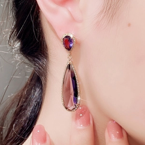 Close-up of a model wearing a vintage pear-cut purple zircon drop earring with gold plating