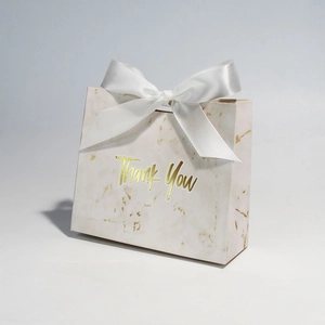 Detail of marble pattern gift bag with gold Thank You text and large white satin bow