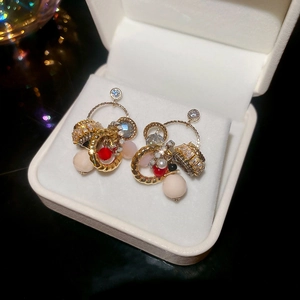 Close-up of vintage gold earrings with red and pink beads in a white jewelry box