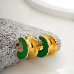 Detailed macro of C-shaped 18K gold earrings with green enamel on natural stone base
