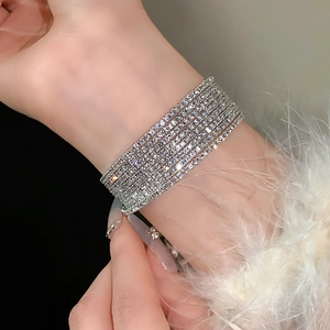 Close-up van een fonkelende zilveren meerlaagse strass-armband om een vrouwenpols