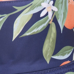Detailed macro view of orange citrus and leaf patterns on navy blue twill fabric