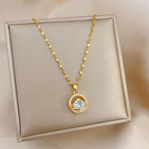 Macro detail of gold planet pendant necklace featuring center gemstone and micro zircons