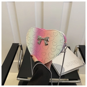 Detail of heart-shaped crossbody bag with pink-green gradient and silver bow decoration