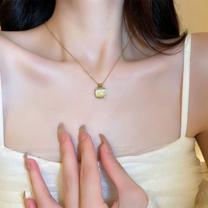 Gros plan d'un collier pendentif carré en pierre d'oeil de chat doré sur le cou