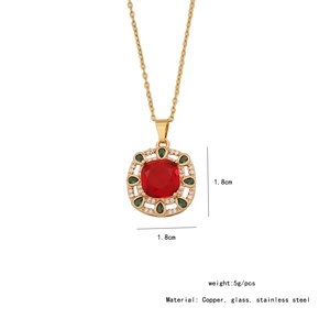 Macro detail of gold vintage pendant with red square gemstone and green accents