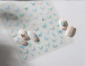 Macro detail of gradient blue butterfly nail stickers with glitter and 3D pearl charms
