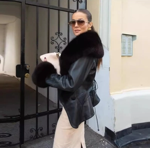 Detail of a chic black leather jacket featuring a plush faux fur collar and cuffs on a model