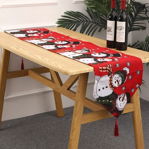 Close-up of red knitted Christmas table runner with snowman patterns and fringe tassels