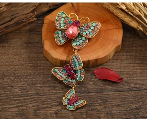 Macro shot of vintage gold butterfly brooch with pink gemstones and colorful rhinestones