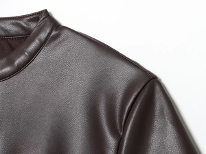 Macro shot of dark brown PU leather dress showing shoulder stitching and fine grain texture