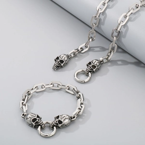 Detailed view of silver skull charms on a stainless steel link chain bracelet and necklace
