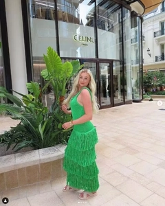 Détail d'une robe longue en maille verte avec franges superposées et coupe ajustée