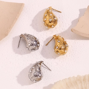 Macro detail of teardrop earrings with lava texture, pearls and diamonds in gold and silver