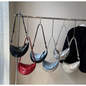 Selection of crescent saddle bags in PU leather and denim displayed on a metal rack