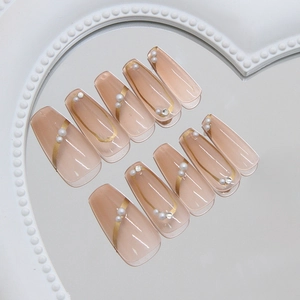 Faux ongles cercueil rose nude avec lignes dorées, perles et strass de luxe