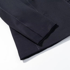 Dettaglio ravvicinato della manica del blazer blu scuro con cuciture bianche a contrasto