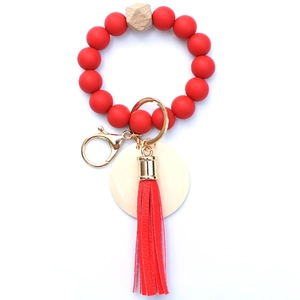 Detail of red silicone bead keychain bracelet with leather tassel and wood tag