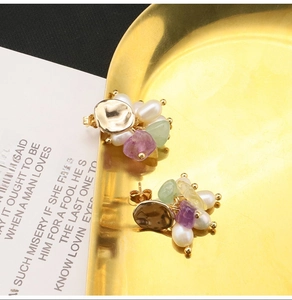 Detail of vintage gold-plated earrings with natural pearls and purple-green stones