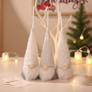 Tre gnomi di Natale in peluche da appendere nei colori bianco e grigio su sfondo festivo