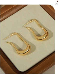 Detail of gold U-shaped curved earrings with high-shine metallic mirror finish
