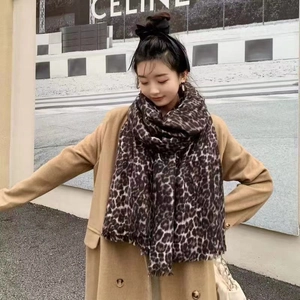 Detail of soft leopard print scarf with fringe edges worn over a khaki wool coat
