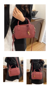 Detail of red hand-woven Boston bag with gold knot hardware and crossbody strap in office
