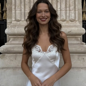 Elegante vestido de satén blanco con encaje en V sobre fondo de columnas de piedra europeas